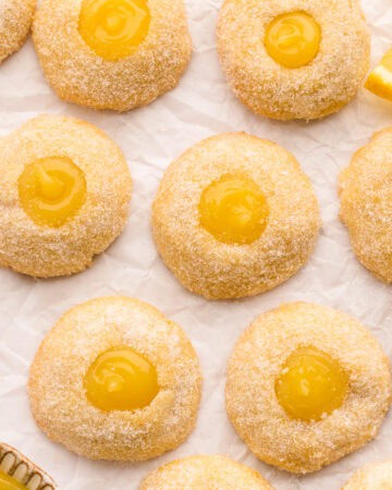 lemon thumbprint cookies (filled with lemon curd) - on a white surface.