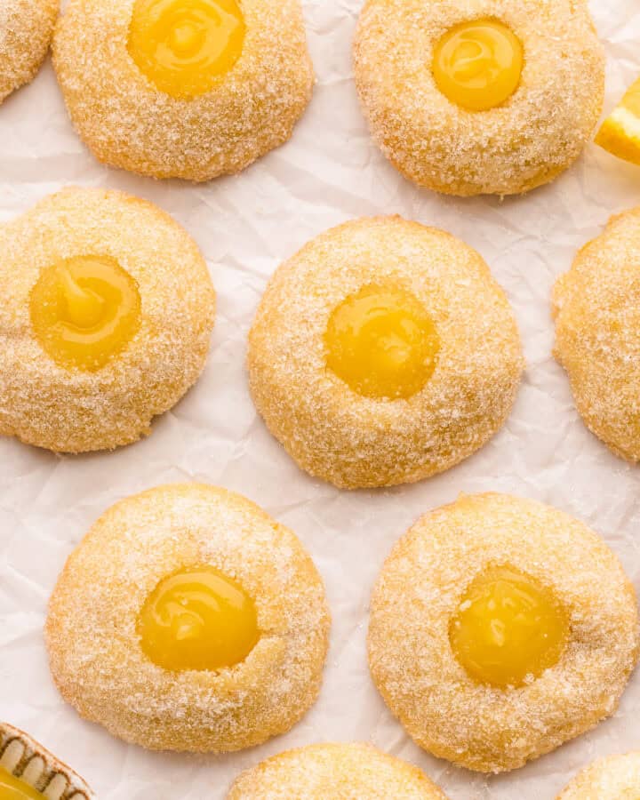 lemon thumbprint cookies (filled with lemon curd) - on a white surface.
