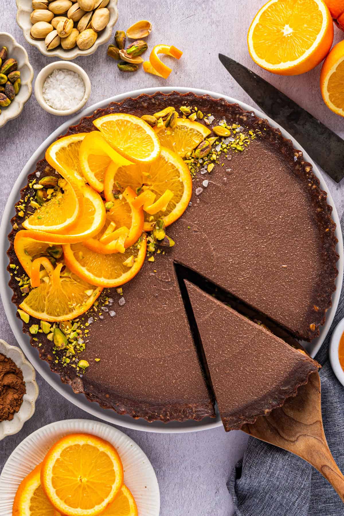 No-Bake Chocolate Tart with Orange Marmalade and Pistachios (Vegan + GF) Chocolate Orange Tart (half of it is topped with fresh orange slices, chopped and whole pistachios, and sea salt).
