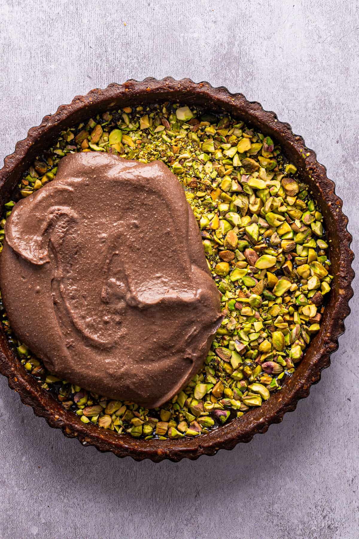 No-Bake Chocolate Tart with Orange Marmalade and Pistachios (Vegan + GF) The tart shell filled with pistachios with a glob of chocolate filling.