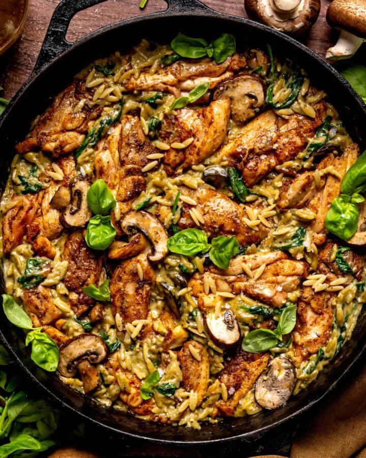 Creamy Chicken Orzo with Spinach, Mushrooms, and Basil Pesto - in a cast iron skillet.