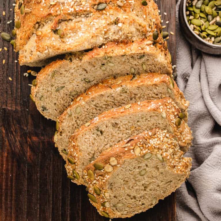 Seeded Rye Bread loaf (sliced) - on a dark wooden background.