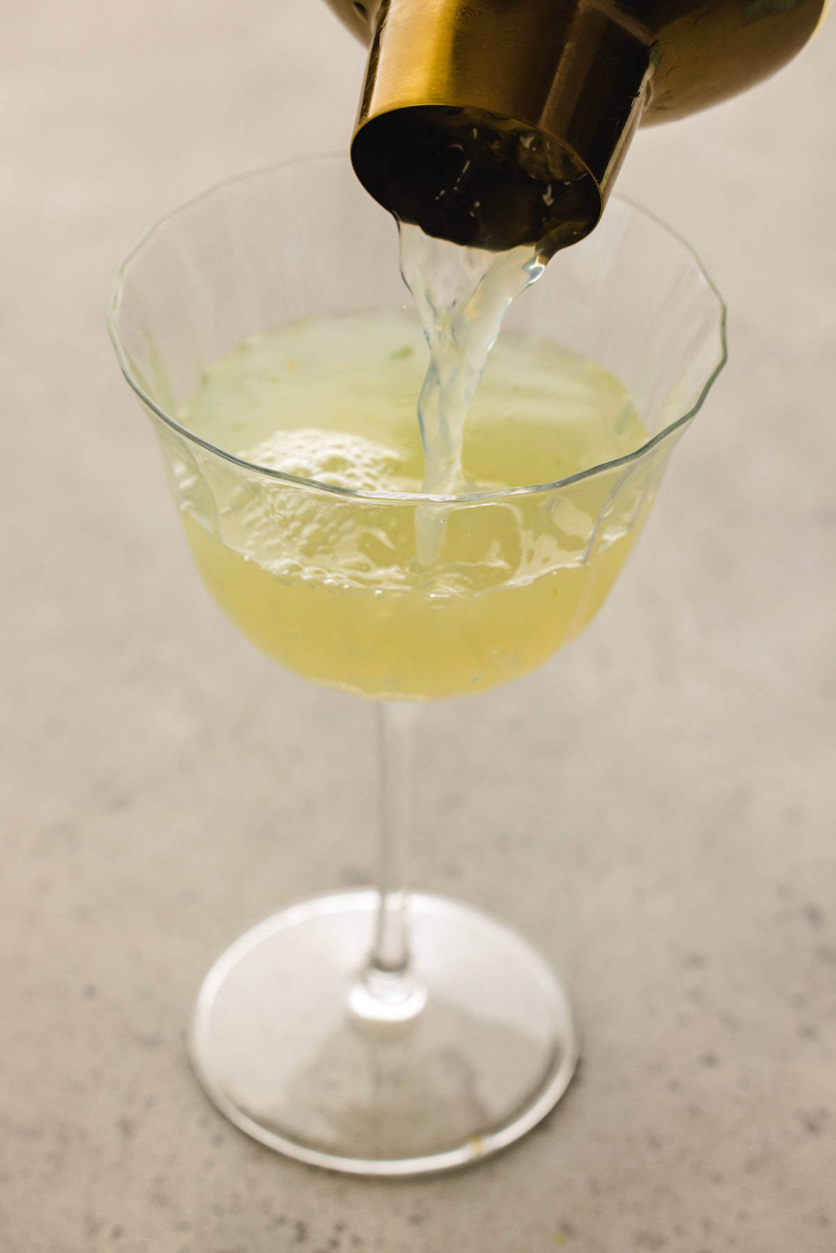 Cucumber Gimlet Pouring the cucumber gimlet cocktail into a glass.