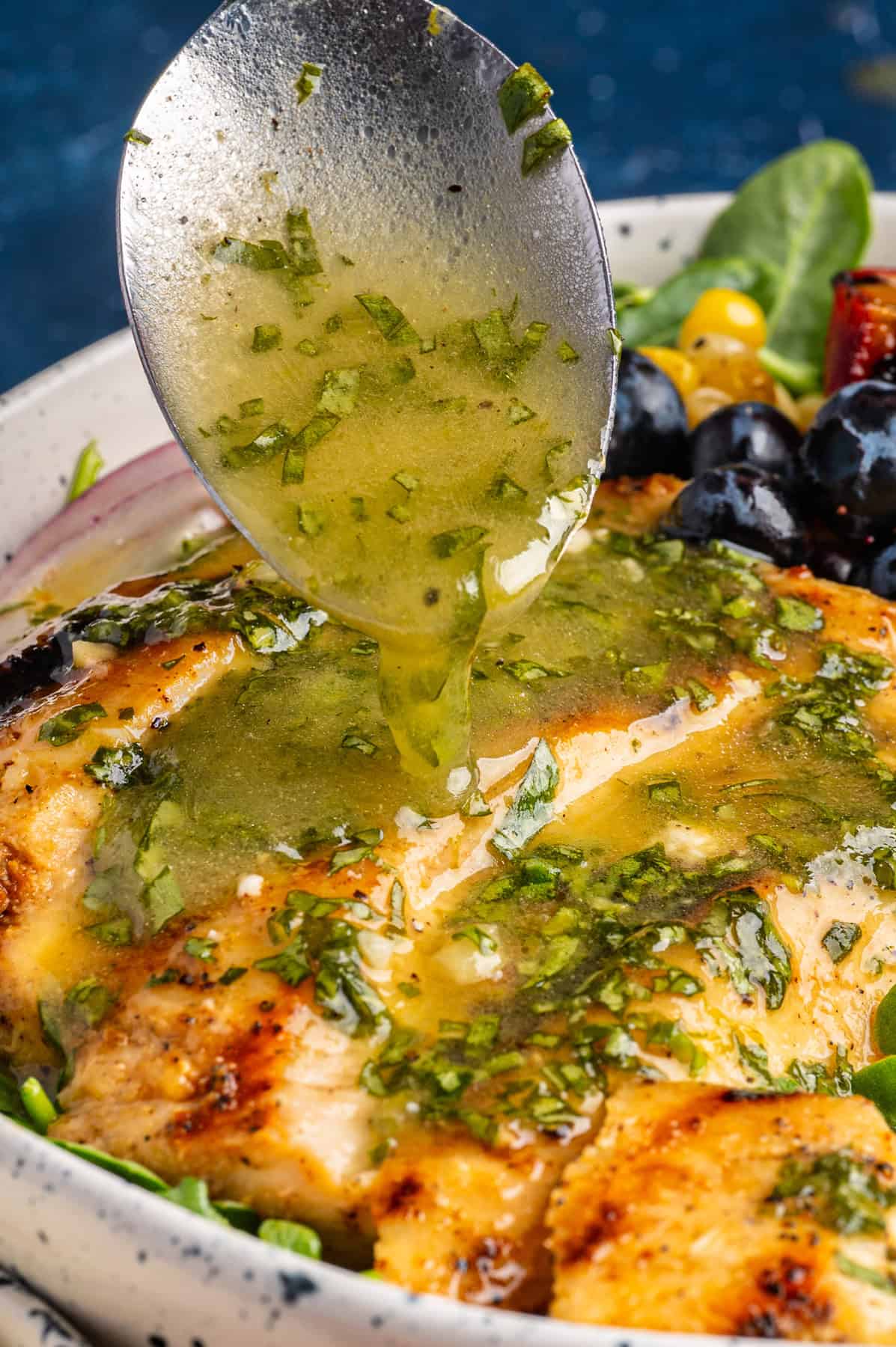 Grilled Chicken and Peach Salad with Lime-Basil Dressing Grilled Chicken and Peach Salad with Corn, Arugula, Blueberries, Feta, Pecans in a bowl, with Lime Basil Vinaigrette dressing being poured over the salad.