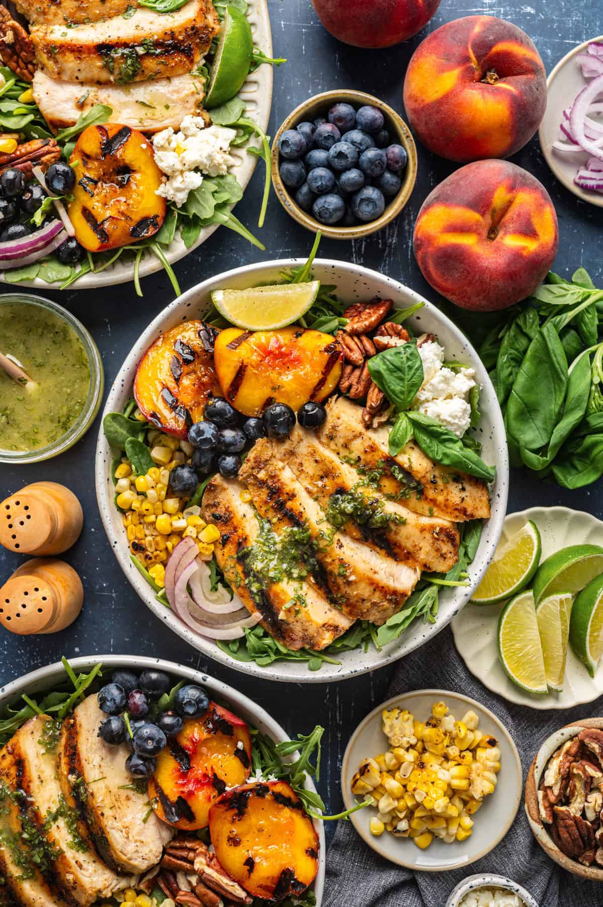 Grilled Chicken and Peach Salad with Lime-Basil Dressing Grilled Chicken and Peach Salad with Corn, Arugula, Blueberries, Feta, Pecans, and Lime Basil Vinaigrette - in a white bowl.