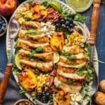 Grilled Chicken and Peach Salad with Corn, Arugula, Blueberries, Feta, Pecans, and Lime Basil Vinaigrette - on a large white platter.