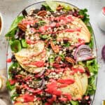 Simple Green Salad with Apples, Dried Cherries, Goat Cheese, Pecans, and Raspberry Vinaigrette - on a large white platter.