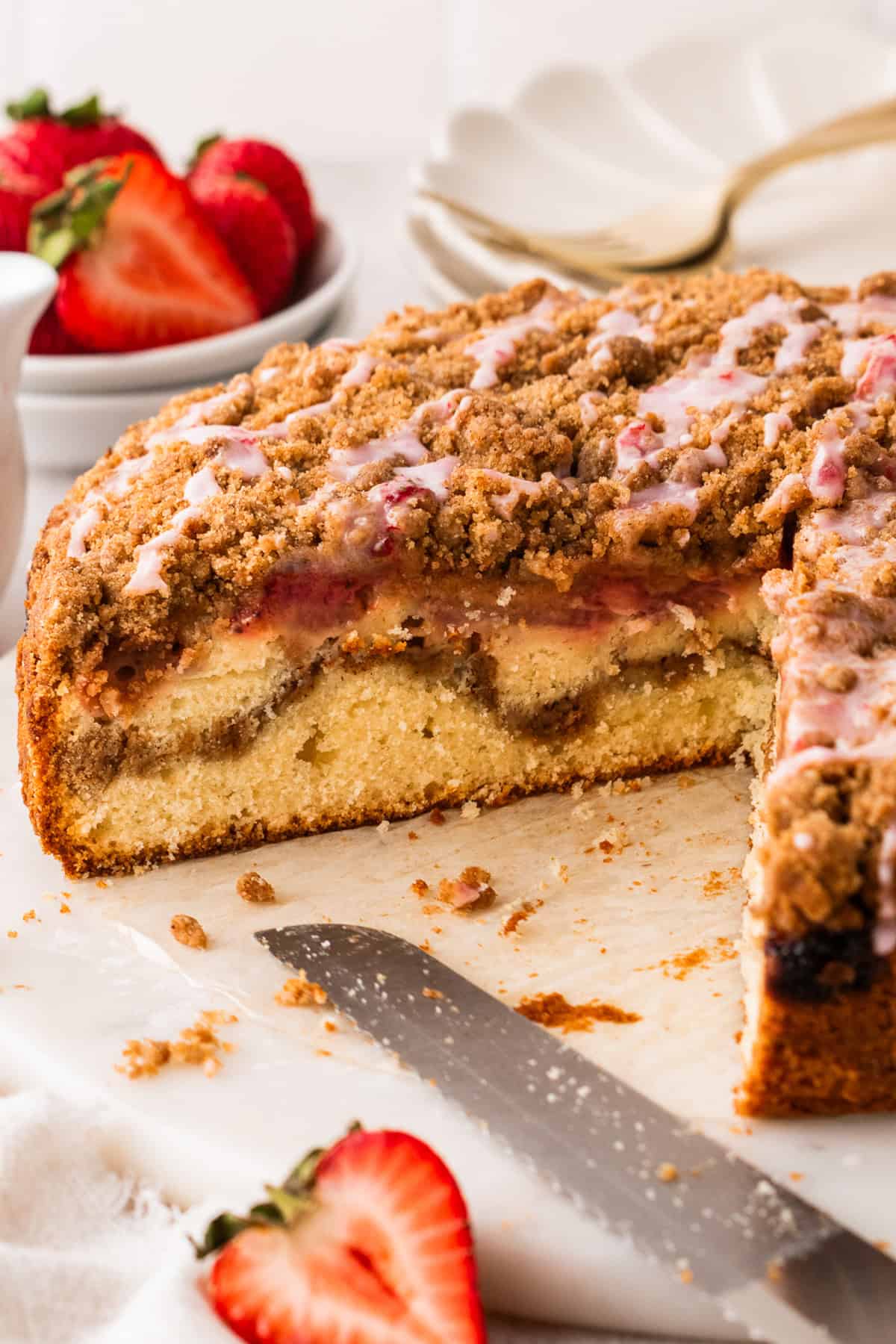 Strawberry Coffee Cake topped with streusel and pink strawberry glaze (with a large slice cut out).