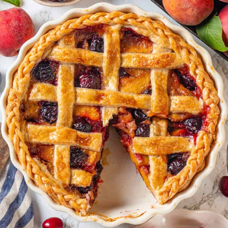 Cherry Peach Lattice Pie (with one slice cut out) in a white pie dish.