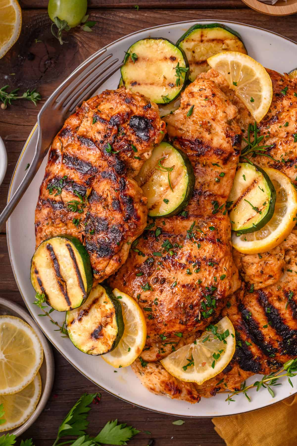 Grilled Chicken Breasts Grilled Chicken Breasts with grilled zucchini rounds on a white plate.