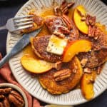Peach Pancakes with Cinnamon Maple Syrup, Peach Slices, Butter, and Pecans - on a white plate.