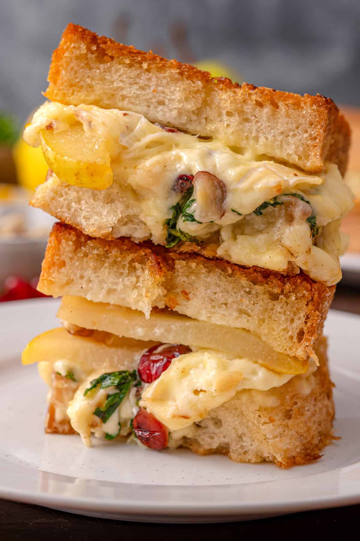 Pear Grilled Cheese Sandwich (with brie cheese, nuts, arugula, and dried cranberries) - on a white plate.