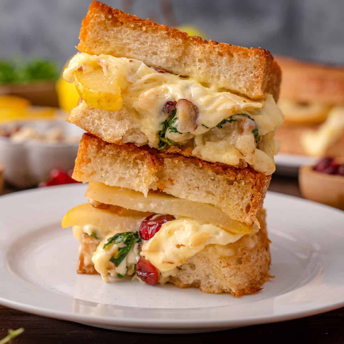 Pear Grilled Cheese Sandwich (with brie cheese, nuts, arugula, and dried cranberries) - on a white plate.