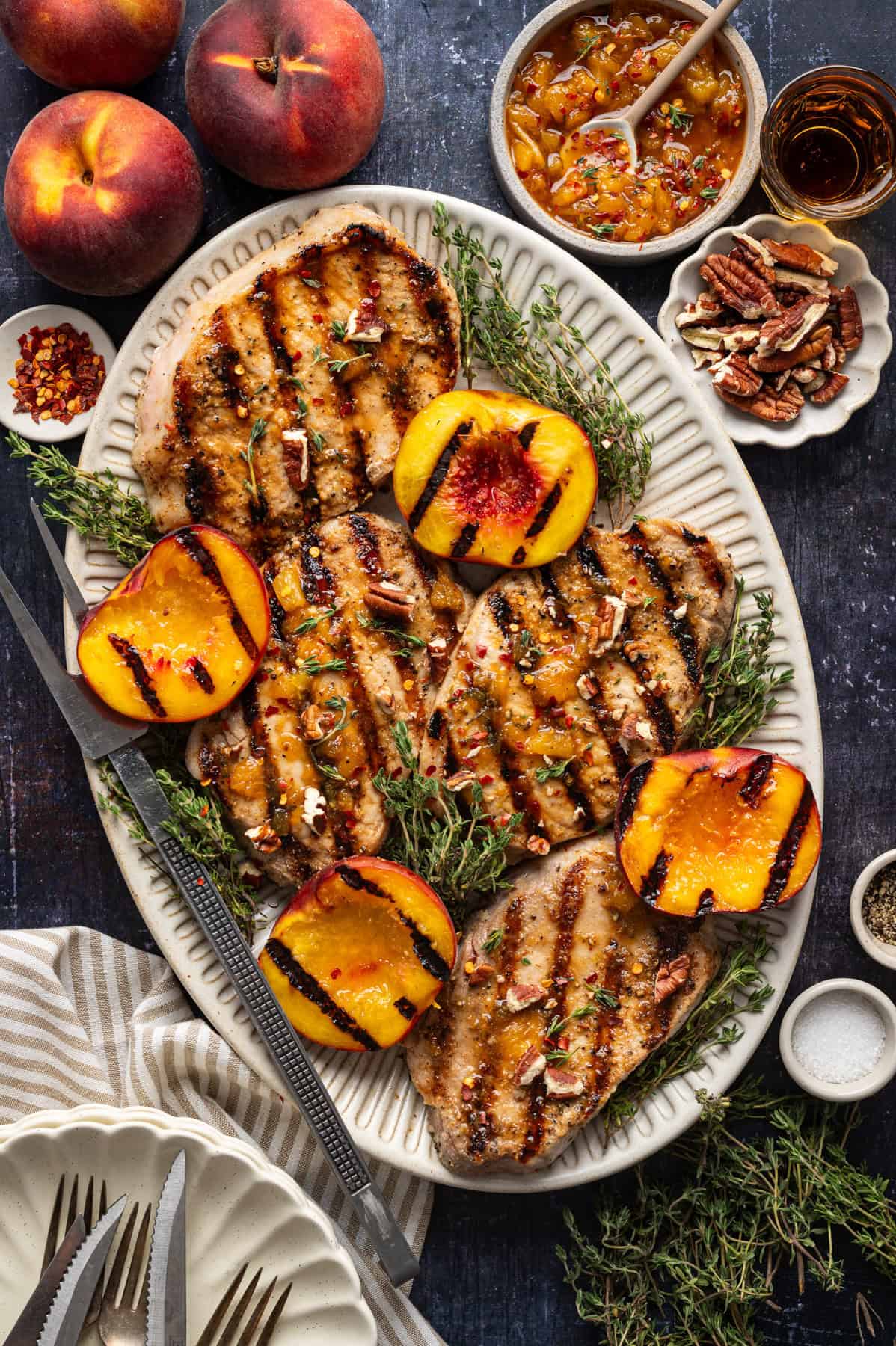 Pork Chops with Peaches and Bourbon Glaze Grilled Pork Chops with Grilled Peaches and Bourbon Glaze - on a white platter.