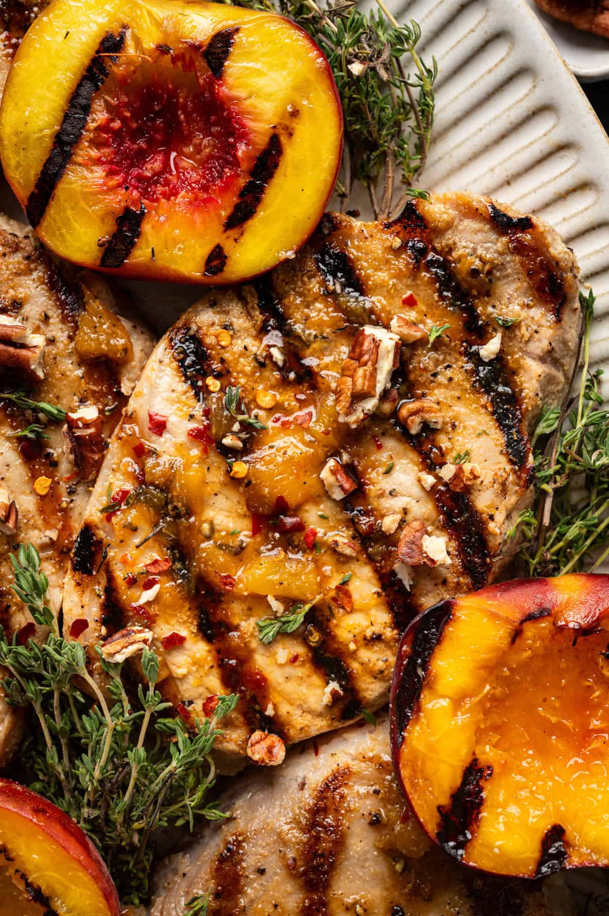 Pork Chops with Peaches and Bourbon Glaze Grilled Pork Chops with Grilled Peaches and Bourbon Glaze on a white platter.