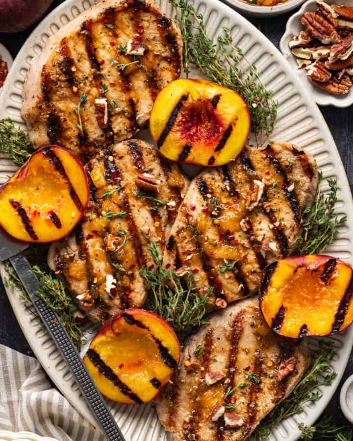 Grilled Pork Chops with Grilled Peaches and Bourbon Glaze - on a white platter.