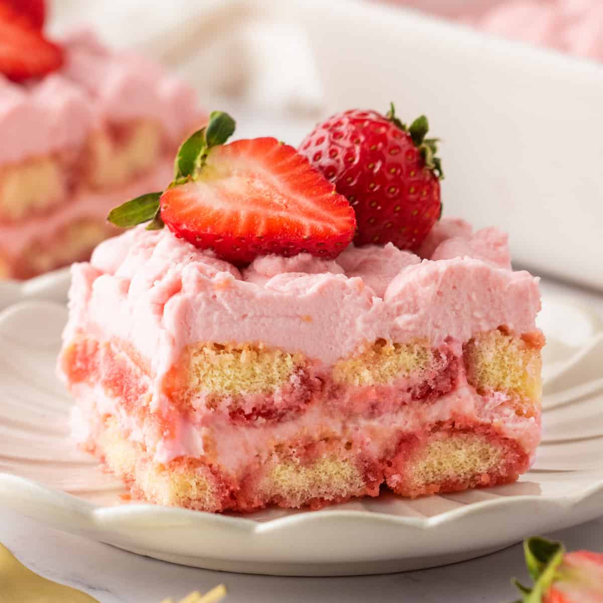 Strawberry Tiramisu A slice of Strawberry Tiramisu (topped with fresh sliced strawberries) on a white plate.