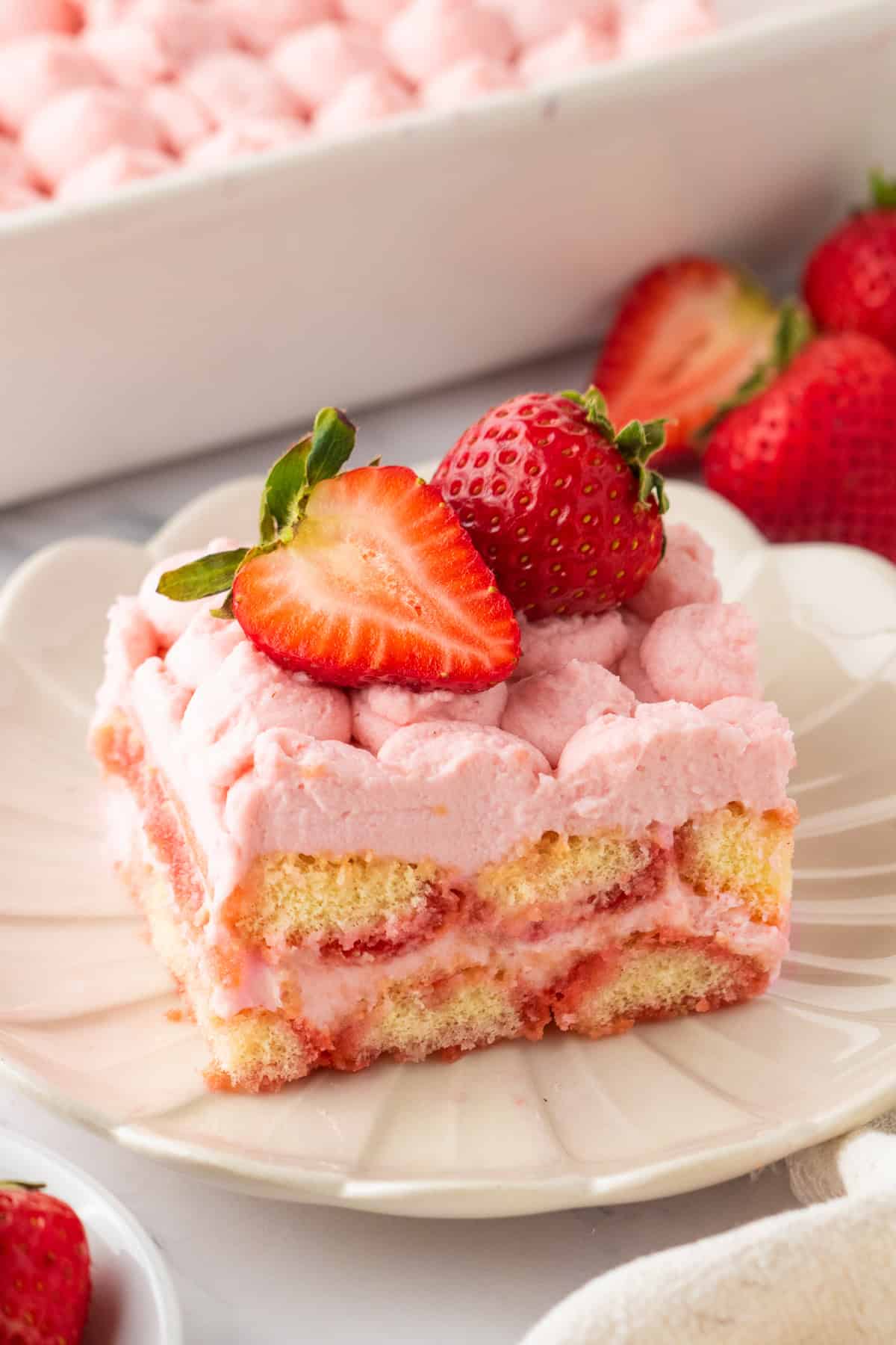 How to Make Strawberry Tiramisu A slice of Strawberry Tiramisu (topped with fresh sliced strawberries) on a white plate.