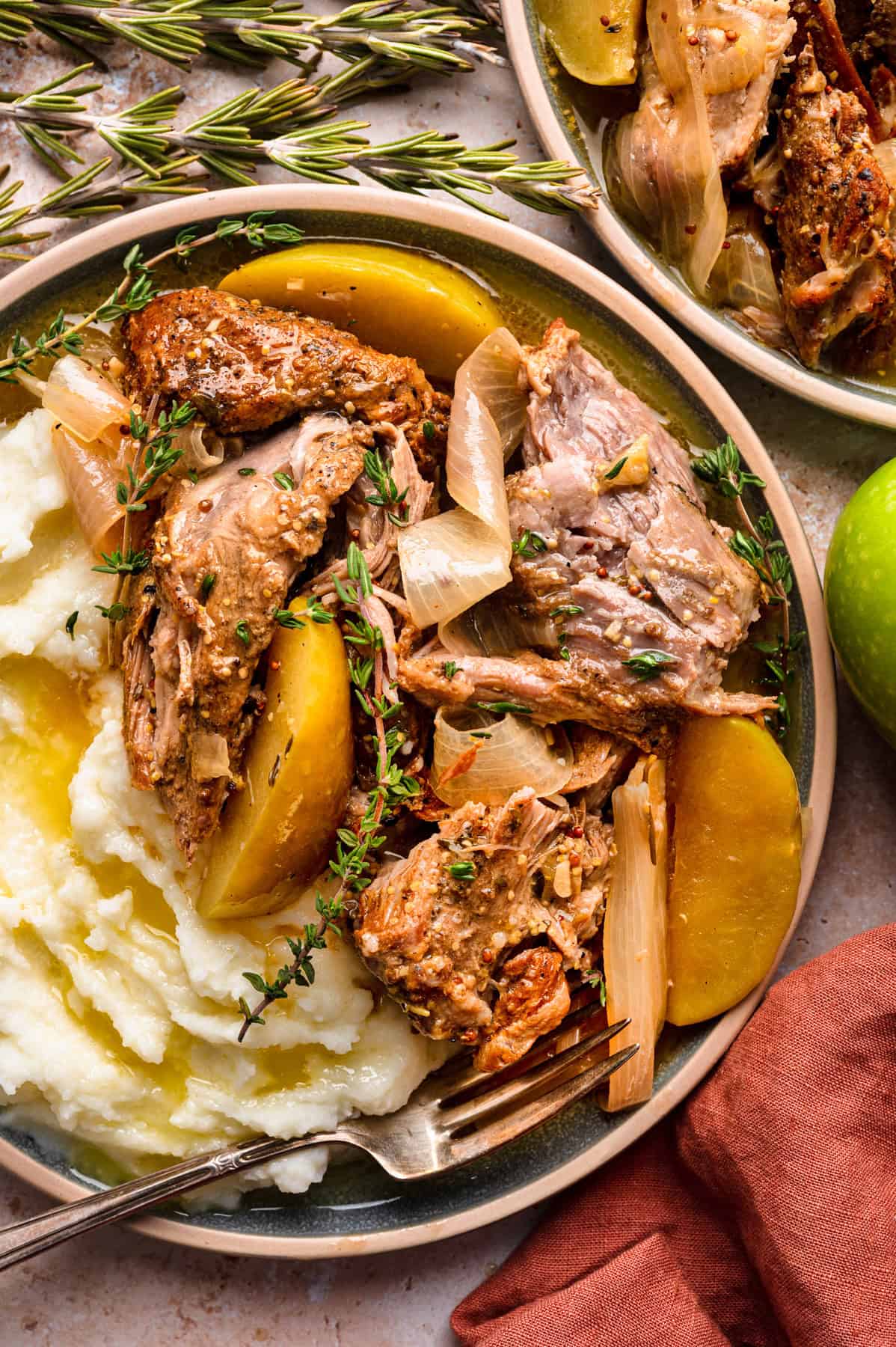 Apple Cider Braised Pork Shoulder with Sliced Apples and mashed potatoes - on a plate.