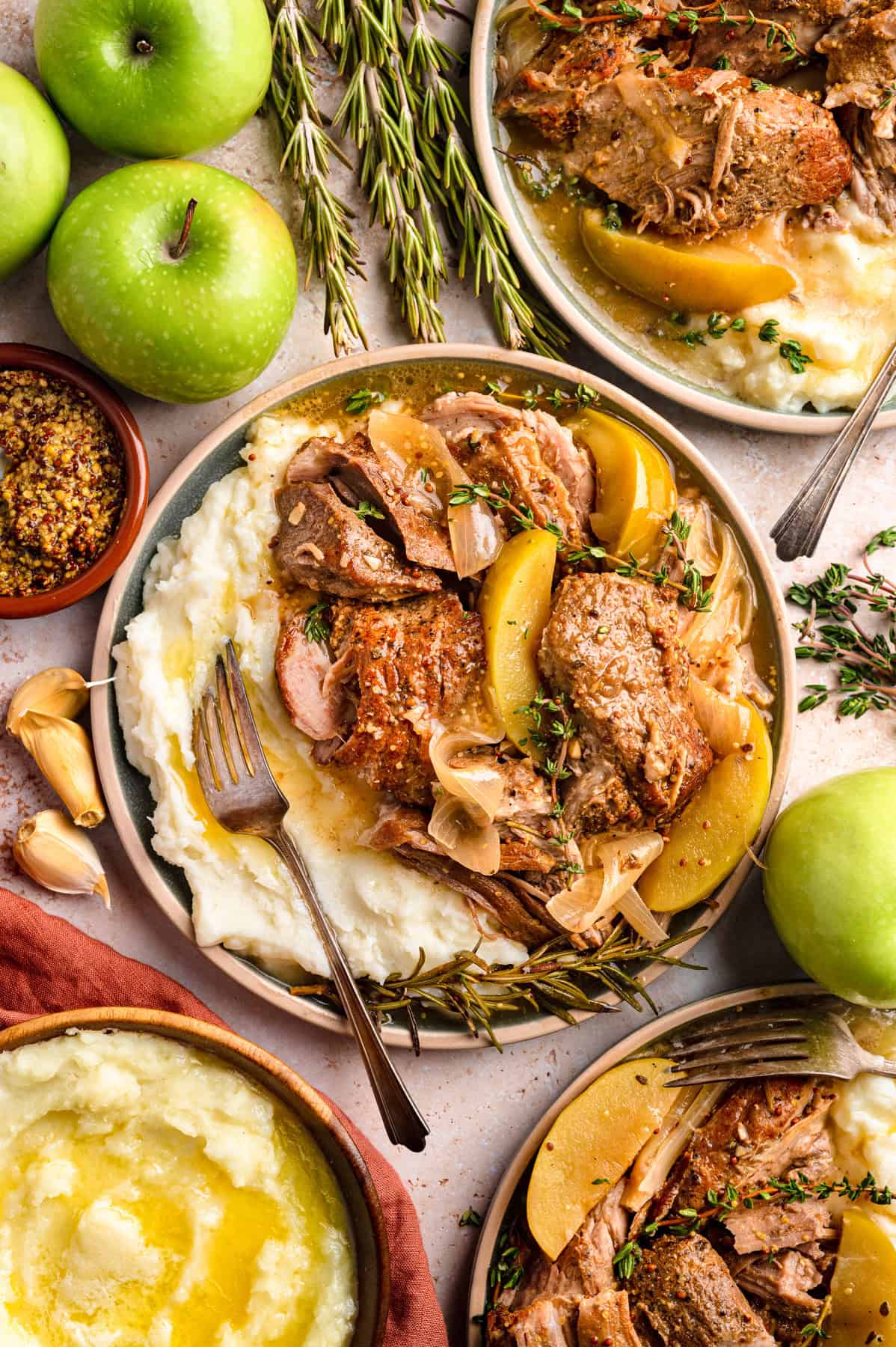Apple Cider Braised Pork Shoulder with Sliced Apples and mashed potatoes - on 3 plates.