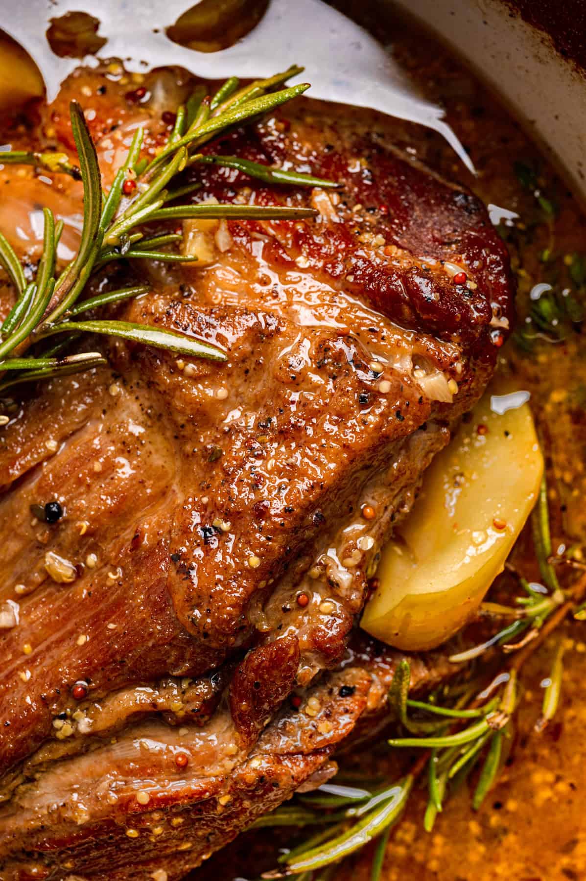 Apple Cider Braised Pork Shoulder with Sliced Apples in a Dutch oven.