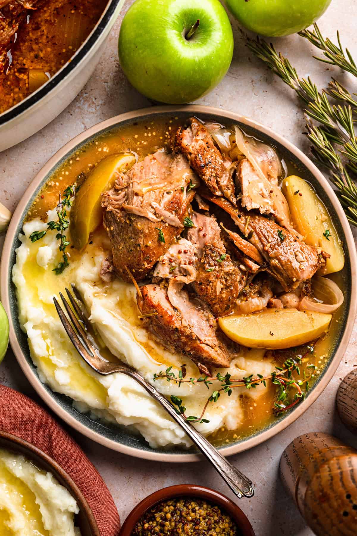 Apple Cider Braised Pork Shoulder with Sliced Apples and mashed potatoes - on a plate.