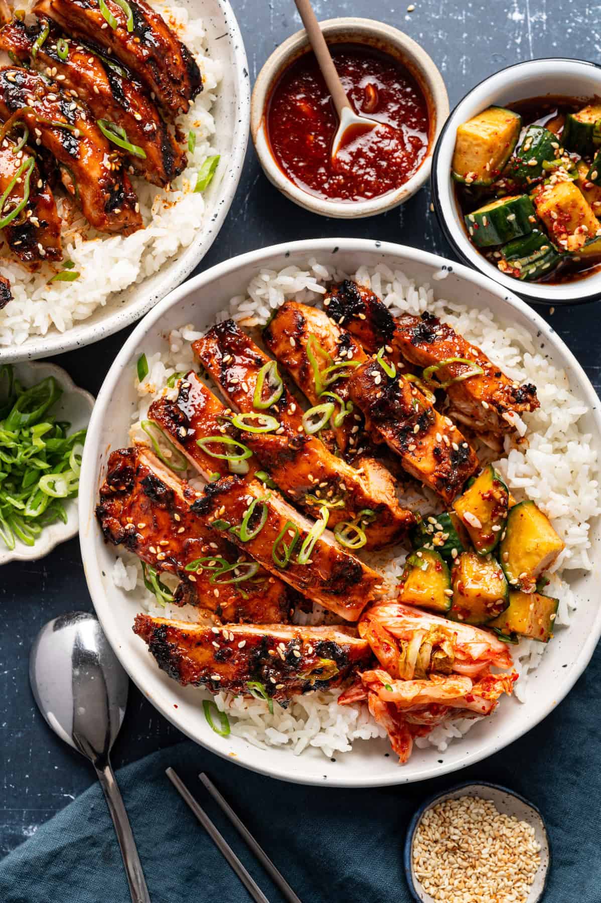 Korean BBQ Chicken with rice, kimchi, and sliced cucumber in a bowl.