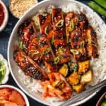 Korean BBQ Chicken with rice, kimchi, and sliced cucumber in a bowl.