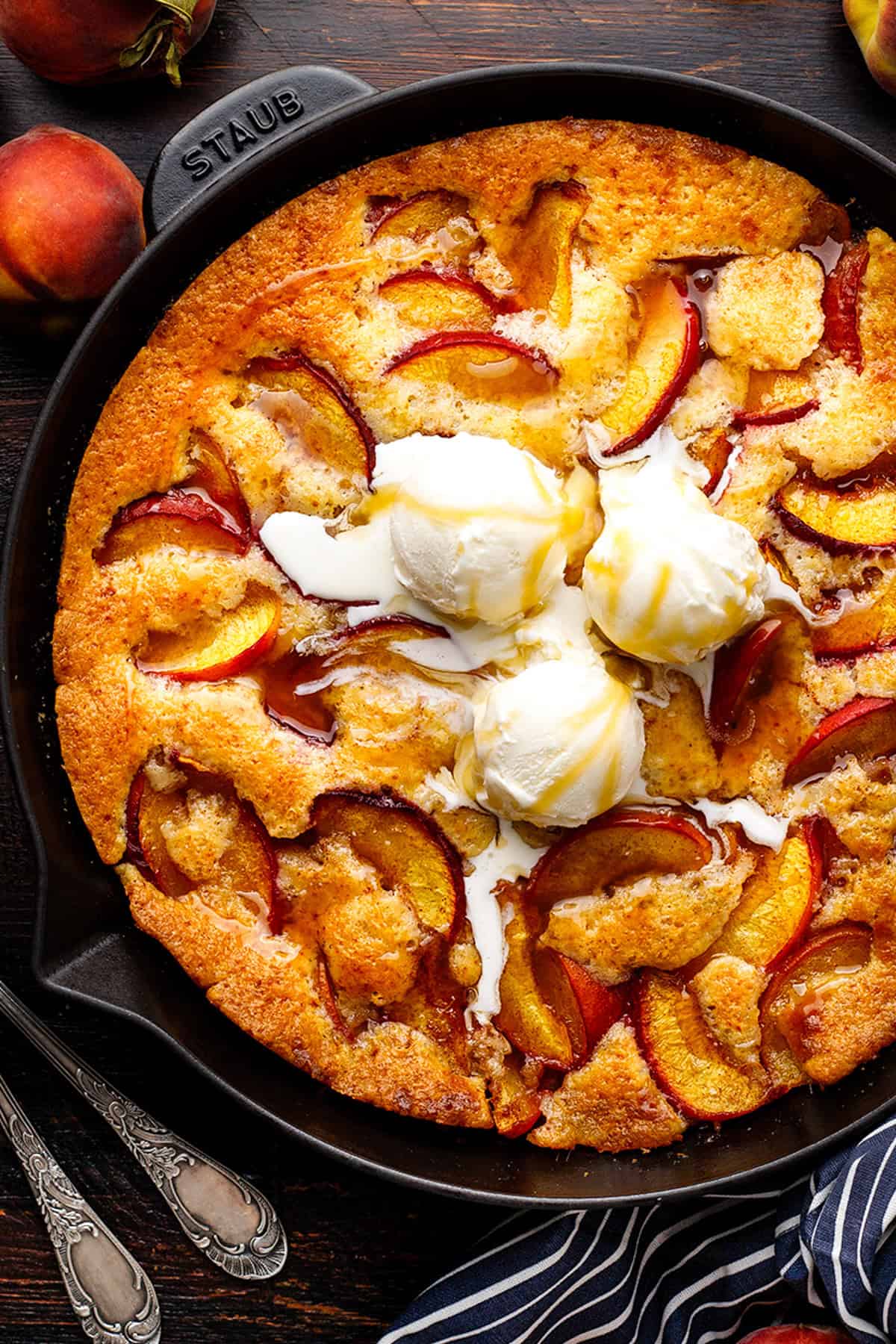 Peach Cobbler topped with ice cream in a black cast iron skillet.