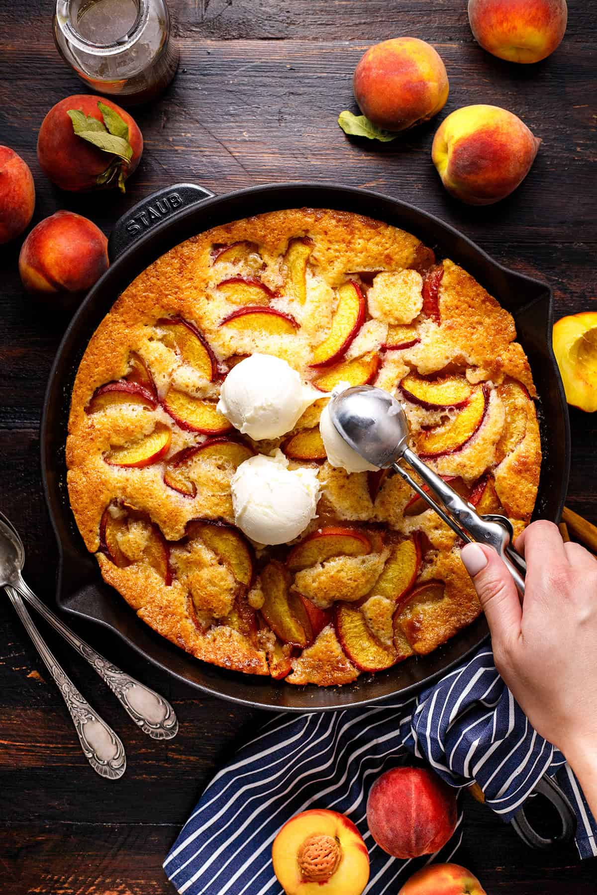 Peach Cobbler topped with ice cream in a black cast iron skillet.