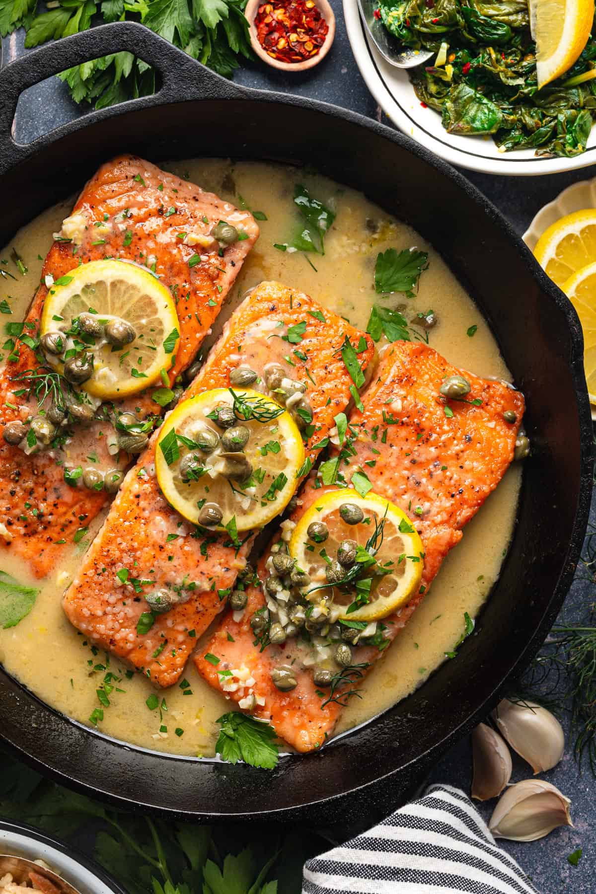 Salmon Piccata Salmon Piccata (3 salmon fillets topped with capers and lemon slices) in a cast iron skillet.