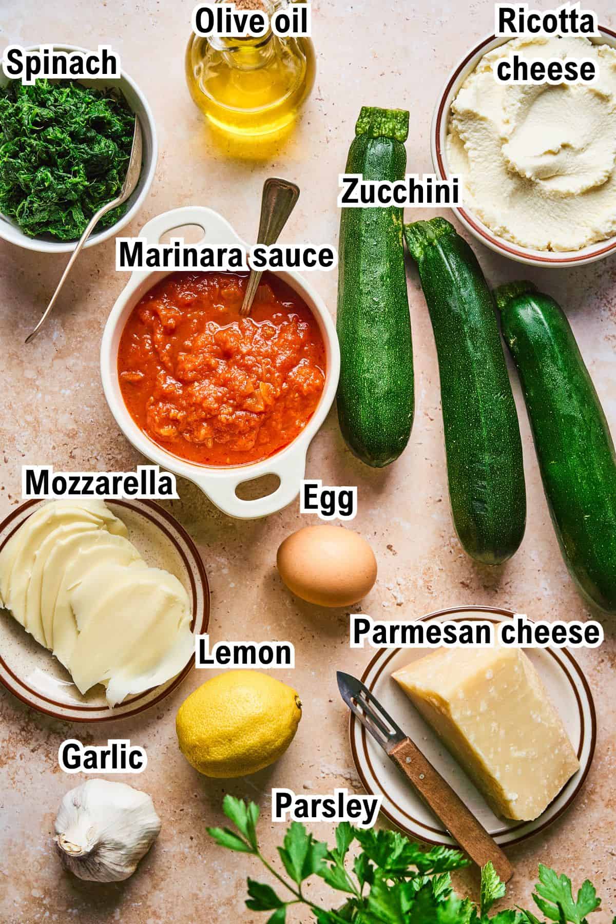 The Ingredients for Zucchini Rollatini This photo shows the ingredients for Zucchini Rollatini: spinach, olive oil, ricotta cheese, zucchini, marinara sauce, mozzarella, egg, lemon, parmesan cheese, garlic, and parsley.