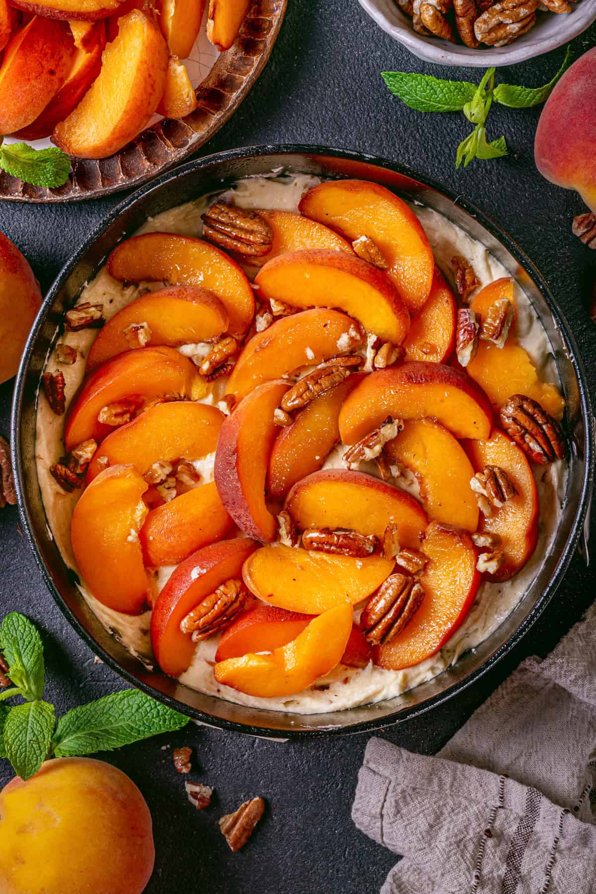 Peach Coffee Cake with Pecan Streusel Cake batter in a spingform pan topped with fresh peach slices and pecans.