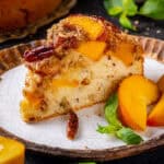 A slice of Peach Coffee Cake topped with Pecan Streusel and Peach Slices - on a plate.