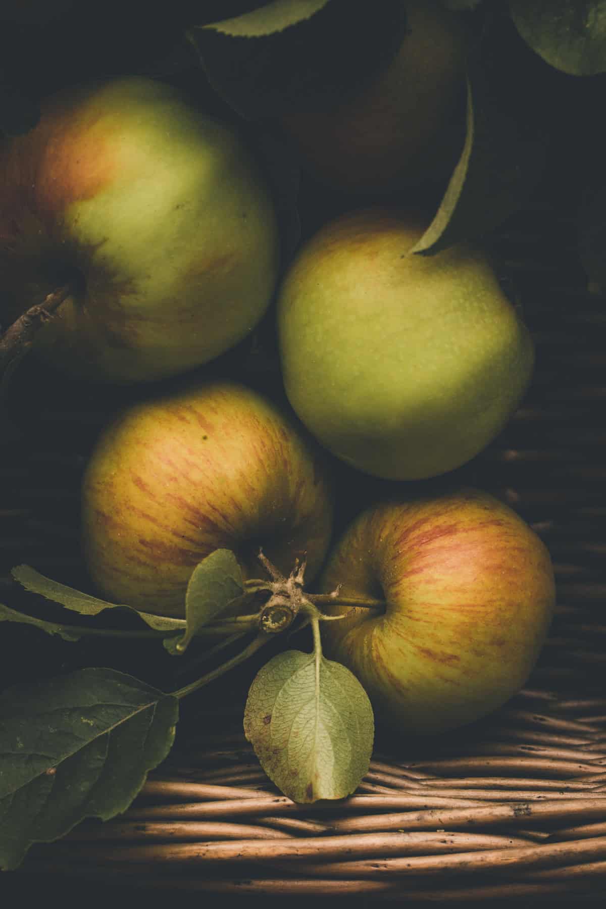 Green and red apples with tree branches in a basket