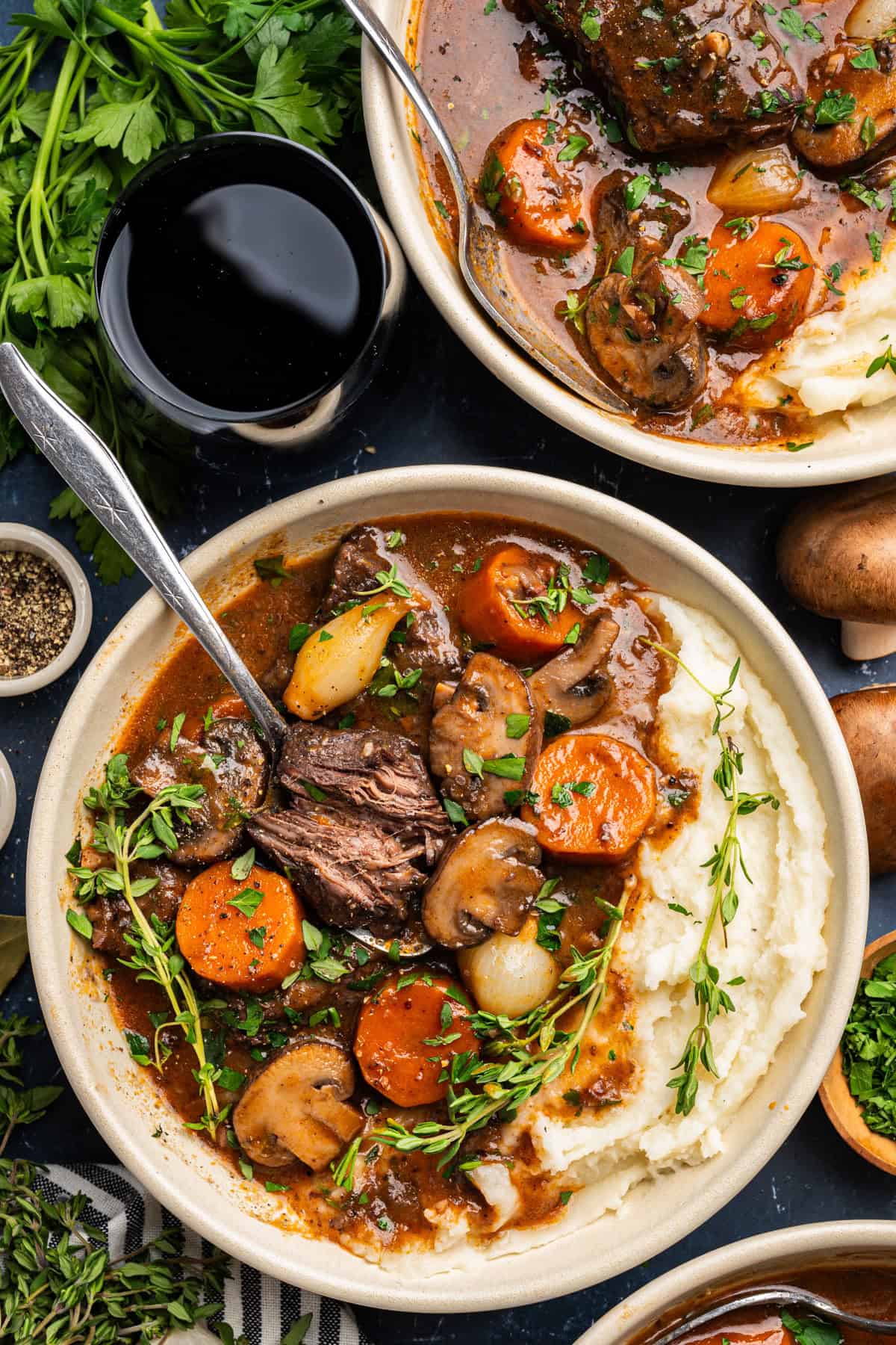 Beef Bourguignon with mashed potatoes in 2 white bowls.