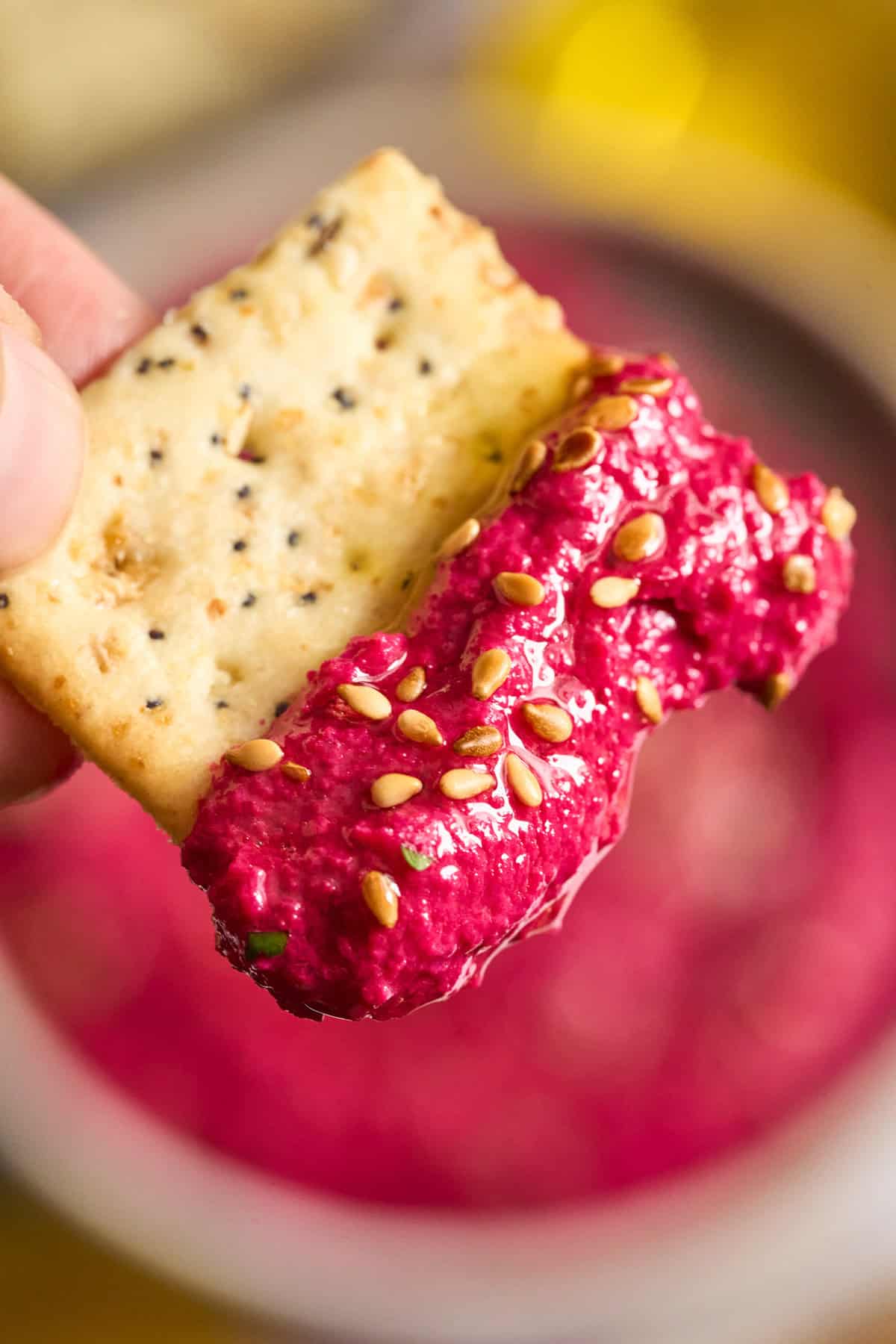 A cracker with Beet Hummus on it.