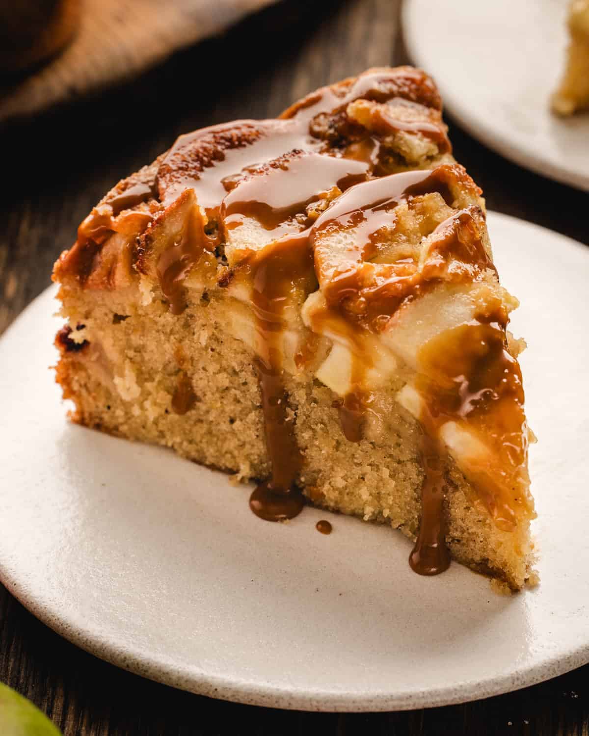 A slice of German Apple Cake drizzled with caramel sauce on a white plate.