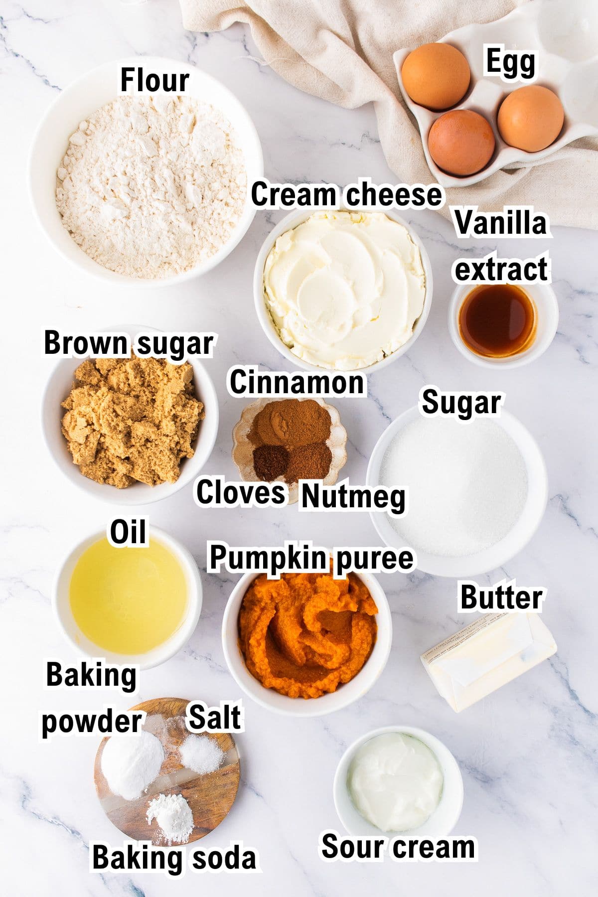The Ingredients for Pumpkin Cream Cheese Bread This photo shows the ingredients for Pumpkin Cream Cheese Bread: including flour, eggs, cream cheese, vanilla, brown sugar, cinnamon, cloves, nutmeg, sugar, oil, butter, pumpkin puree, baking powder, salt, baking soda, and sour cream.