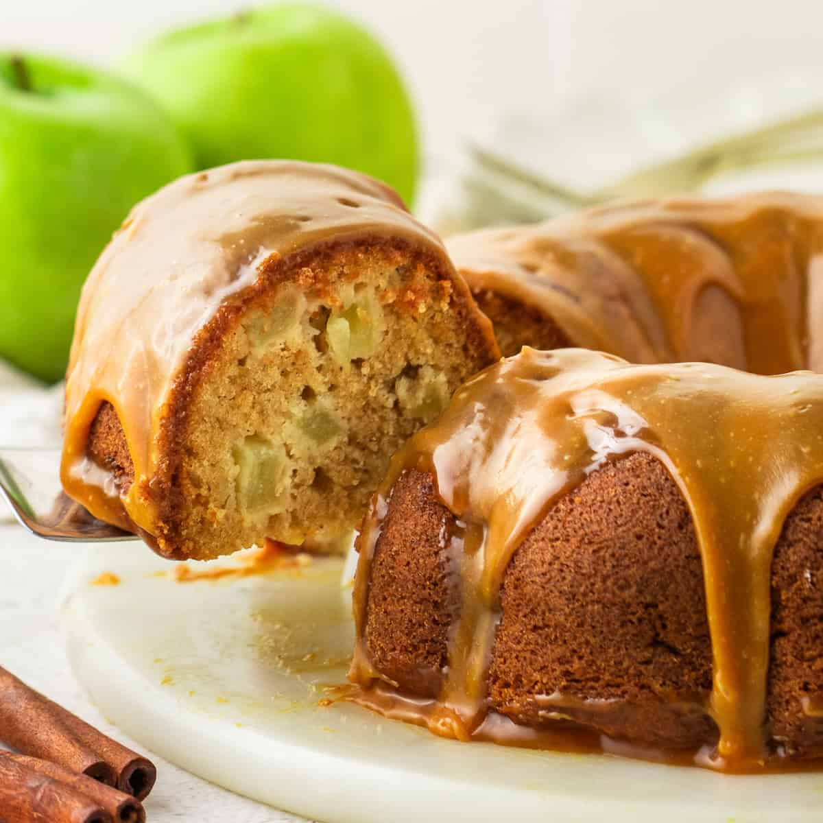 Apple Bundt Cake with Caramel Sauce Apple Bundt Cake with Caramel Sauce with a slice lifted up on a spatula.