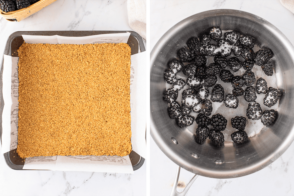 A baking pan lined with parchment paper and filled with a graham cracker crust on the left; a pot with blackberries and sugar on the right, both on a white countertop.