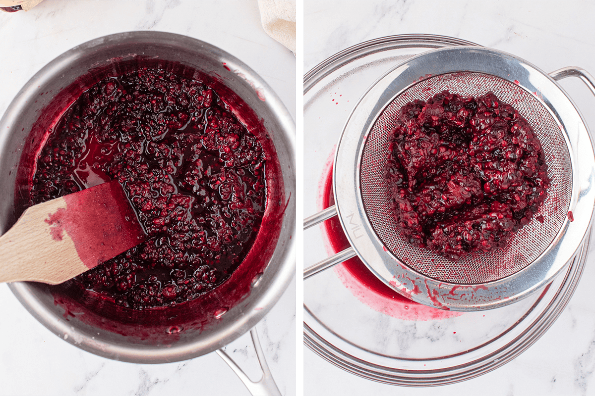 A pot of cooked berry mixture is stirred with a wooden spatula. Next to it, berry pulp is strained through a fine mesh sieve over a bowl, separating the juice from the solids on a white countertop.