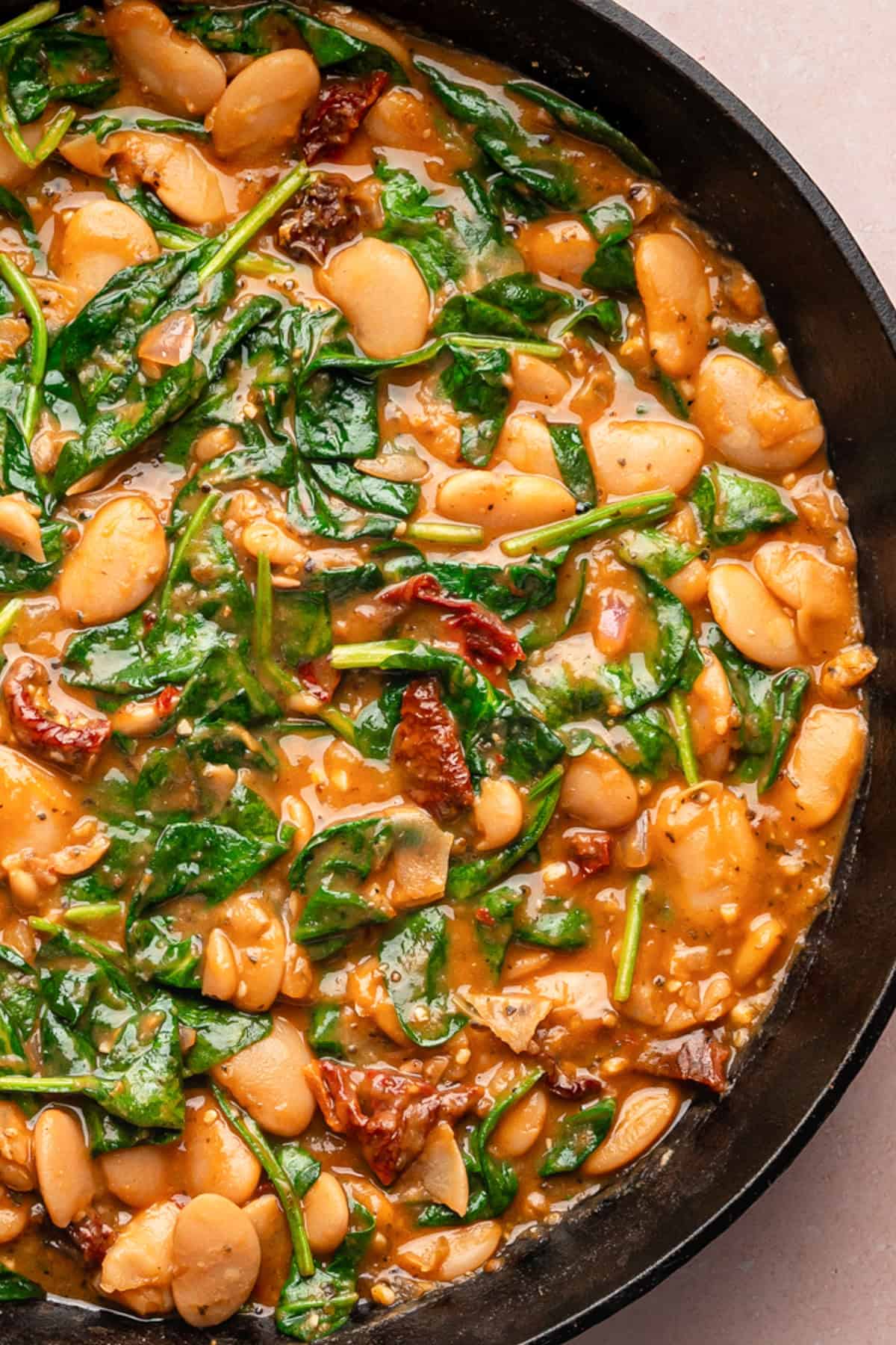 Creamy Butter Beans with Sun-Dried Tomatoes, Spinach, and Parmesan Cream Sauce (Marry Me Beans) - in a cast iron skillet.