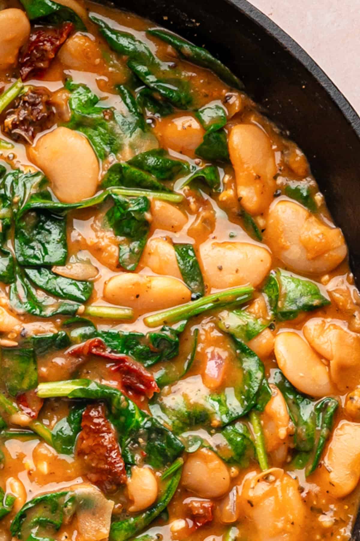 Creamy Butter Beans with Sun-Dried Tomatoes, Spinach, and Parmesan Cream Sauce (Marry Me Beans) - in a cast iron skillet.