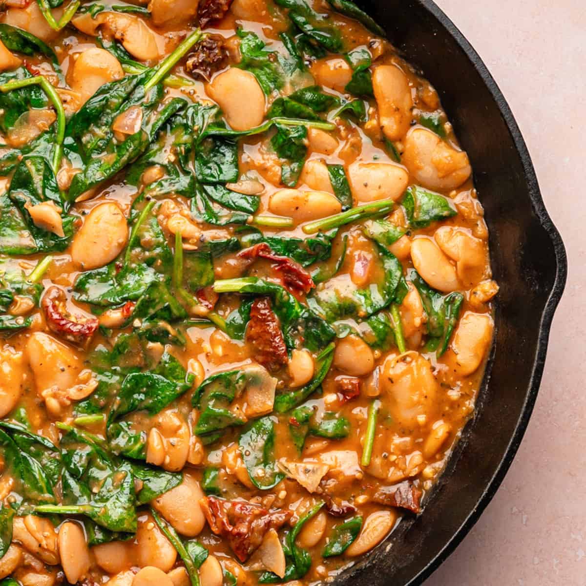 Creamy Butter Beans with Sun-Dried Tomatoes, Spinach, and Parmesan Cream Sauce (Marry Me Beans) - in a cast iron skillet.