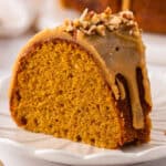 A slice of Pumpkin Bundt Cake Topped with Brown Sugar Glaze and Pecans - on a plate.