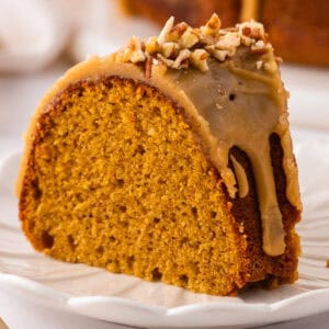 A slice of Pumpkin Bundt Cake Topped with Brown Sugar Glaze and Pecans - on a plate.