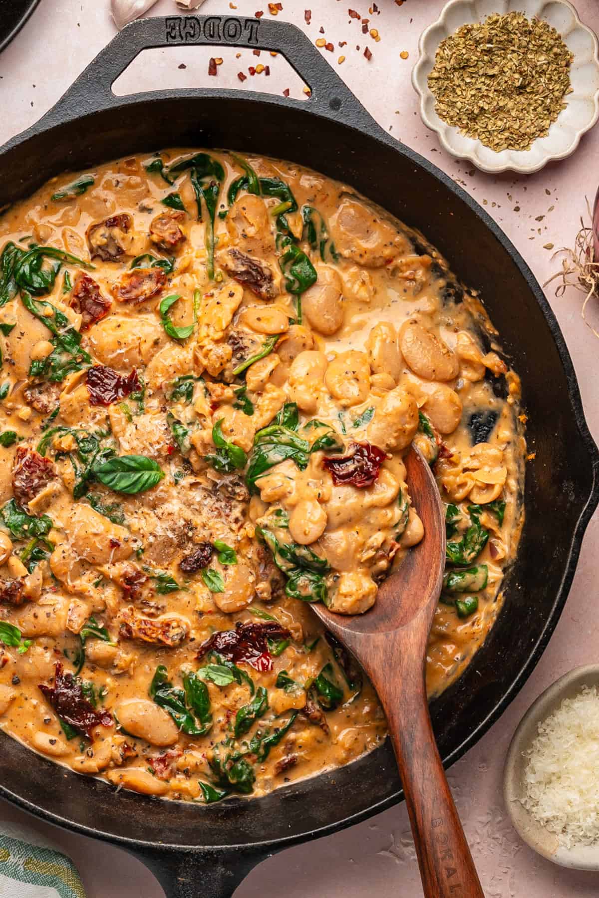 Tuscan Marry-Me Butter Beans with Spinach, Sun-Dried Tomatoes, and Parmesan Cheese - in a cast iron skillet.