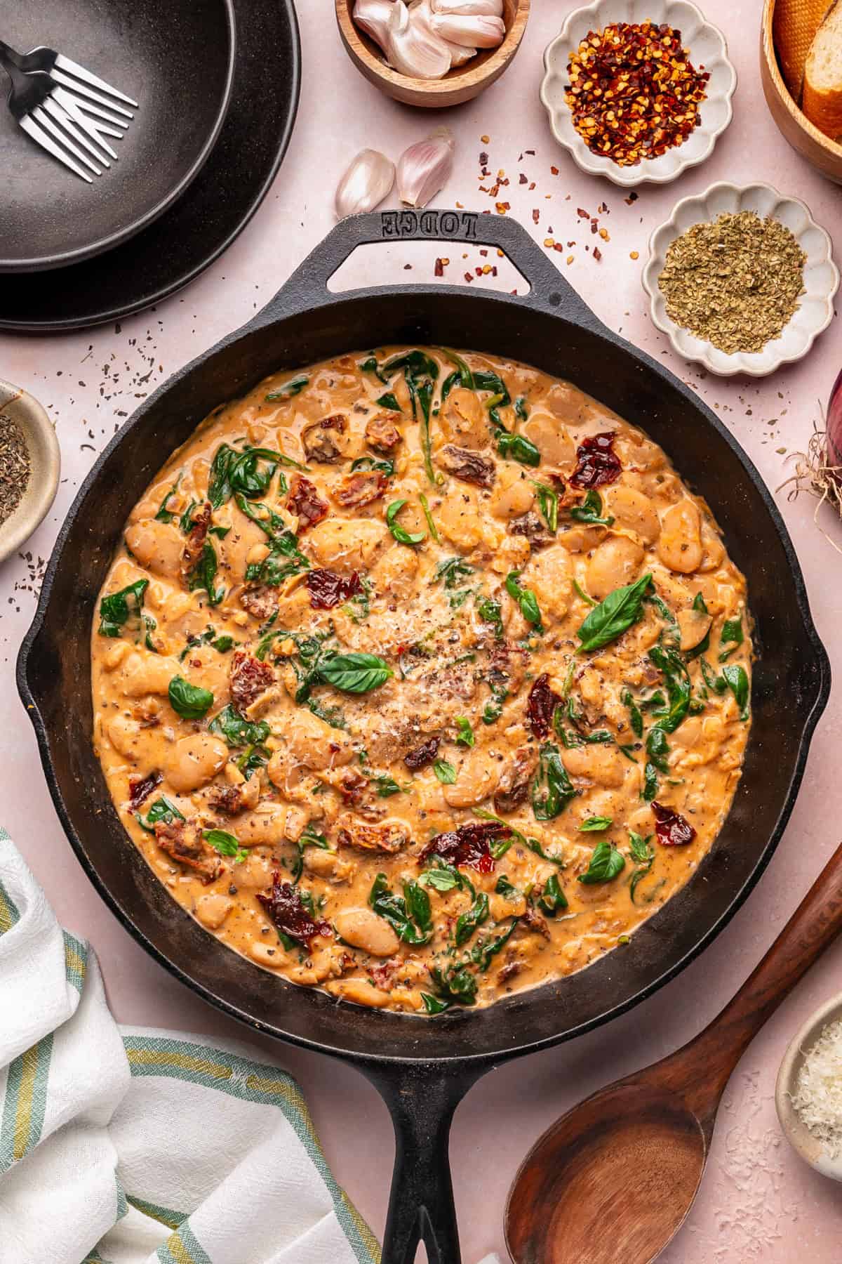 Tuscan Marry-Me Butter Beans with Spinach, Sun-Dried Tomatoes, and Parmesan Cheese - in a cast iron skillet.