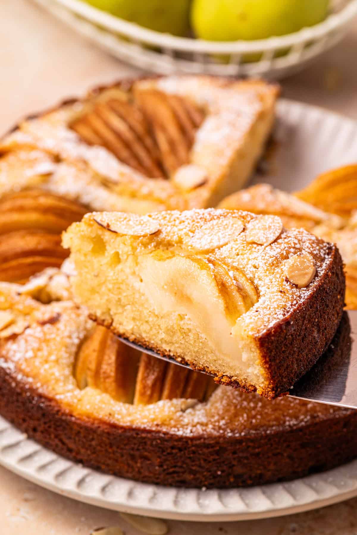 Pear Cake with Almond Flour, Almonds, and Fresh Pears Pear Cake with Almond Flour, Almonds, and Fresh Pears with a slice of cake on a spatula in front of the cake.